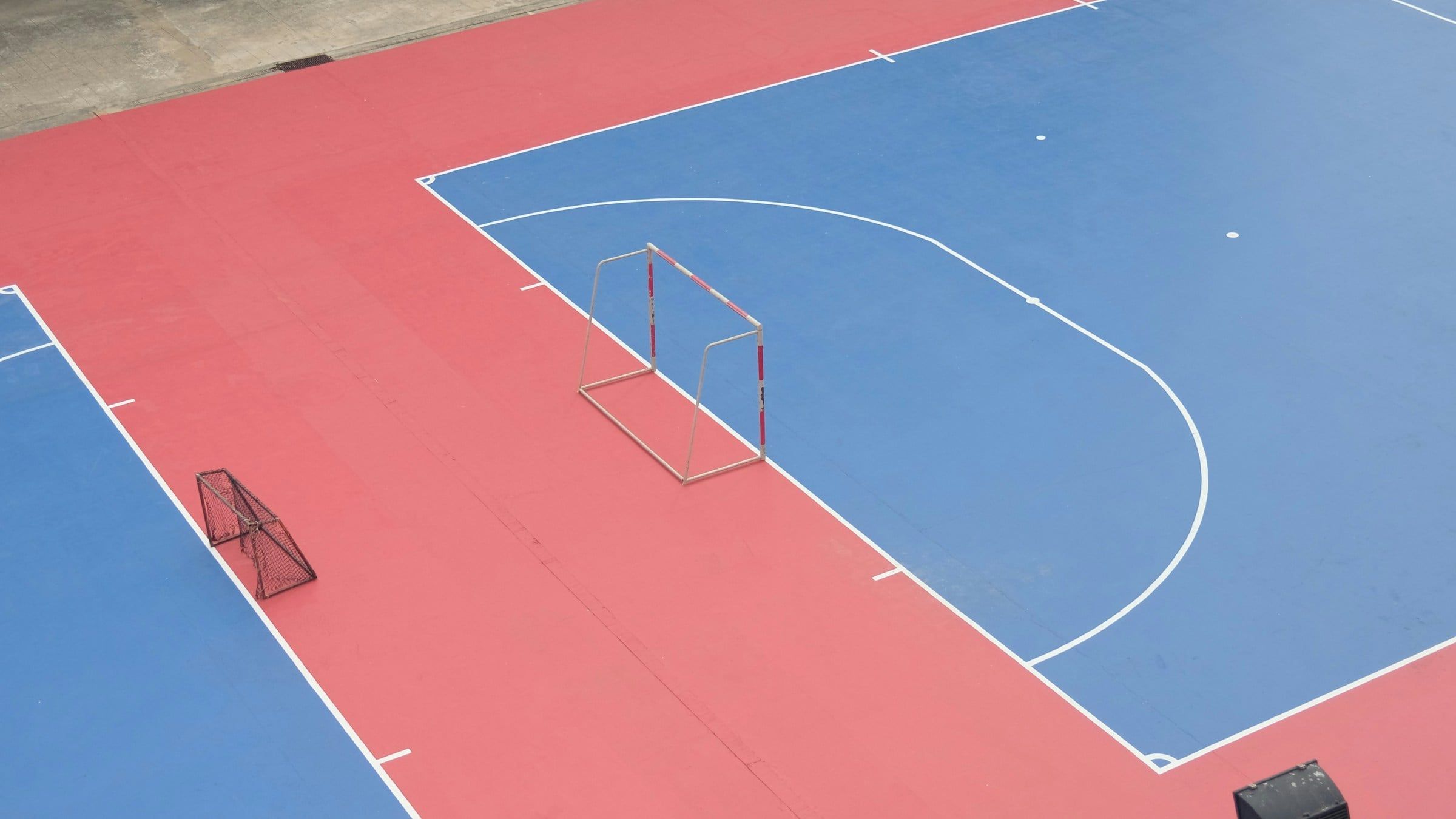 Campo da calcio a 5 visto dall'alto, con le linee bianche sul fondo blu e rosso e le piccole porte con la rete agli angoli